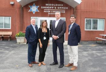 Four people stand outside the front door of the Middlesex Jail & House of Correction.
