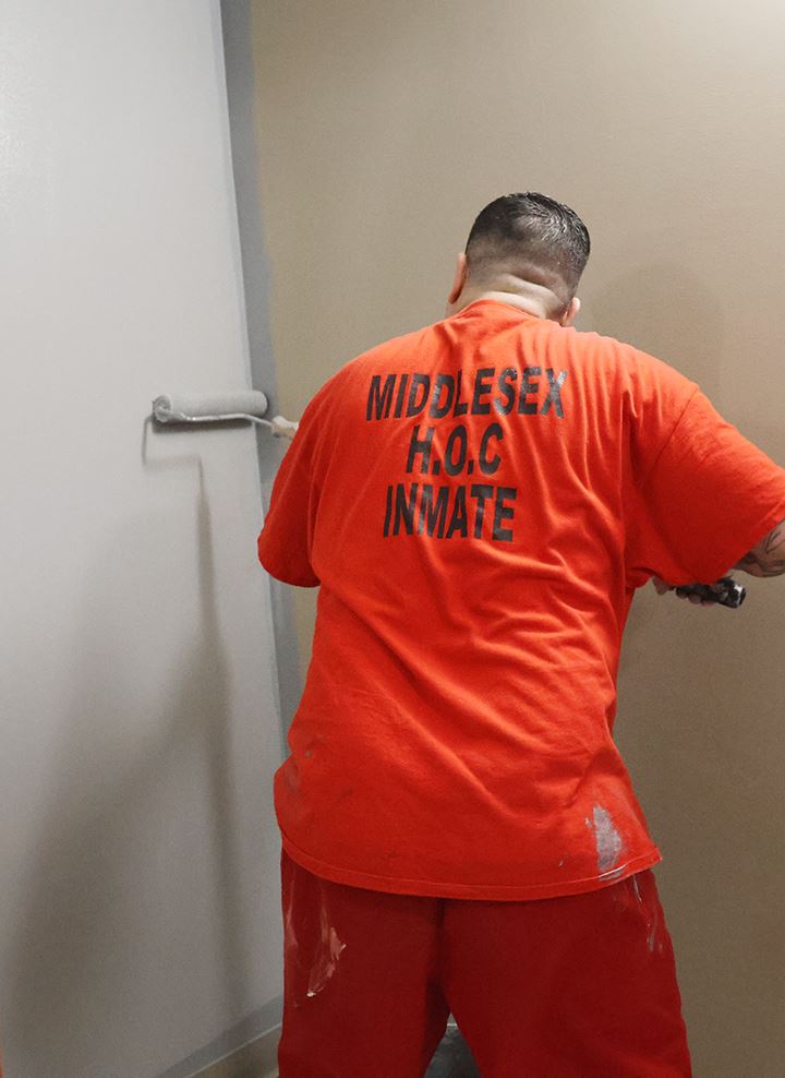 A member of the MSO CWP crew paints a wall with a roller.